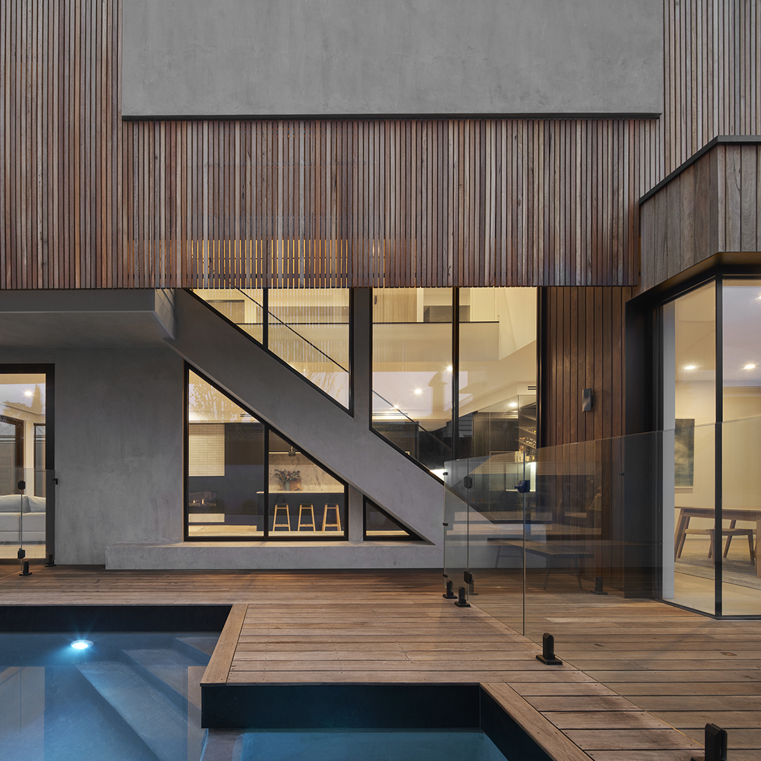contemporary exterior with timber batten and concrete render overlooking pool