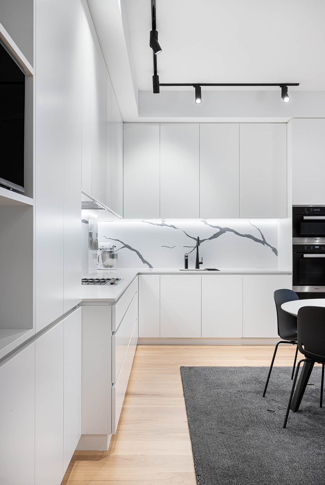 contemporary apartment kitchen white with grande statuario splashbackand miele appliances